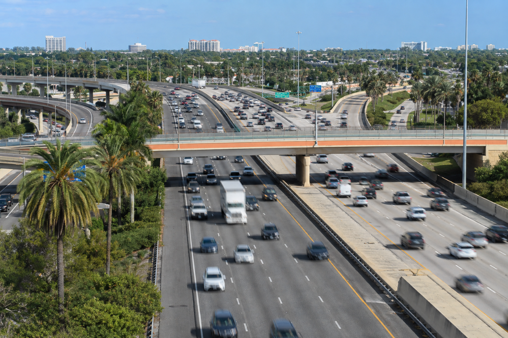 A busy highway filled with numerous cars traveling in various directions under a clear blue sky.